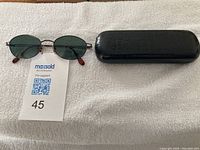 DKNY sunglasses and case shown on white textured fabric, includes lot number tag.