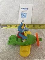 Side view of the Gonzo toy plane showing length with measuring tape and character seated in cockpit.