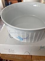 White ceramic soufflé dish with floral motif on box