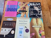 Top view of all 6 paperback books arranged in two rows on a wooden surface.