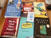 Photo of six paperback books arranged on a wooden surface showing their front covers.
