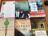 Topview photo showing all six paperback books arranged side-by-side on a wooden surface, titles clearly visible.