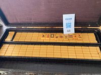 Open carrying case displaying rows of cream-colored Bakelite Mahjong tiles with visible Chinese characters.