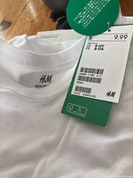 Close-up of white H&M T-Shirt, size 8-10Y, tagged new at $9.99