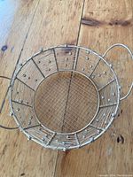 Top-down view of the round wire basket showing mesh bottom and spherical wire decorations on the sides with handles.