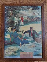Framed antique Adam Scheidt Brewing advertising sign depicting a picnic scene with people and an early car