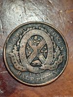 Reverse side of 1837 Bank of Montreal half penny token showing City of Montreal arms within an oval wreath and bank identification inscription.