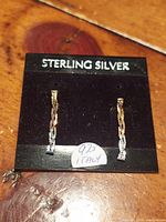 Pair of thin sterling silver dangle earrings on a black card labeled 'Sterling Silver' with a '925 Italy' sticker.