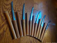 Six Japanese vintage steak knives with hardwood handles laid out showing the curved stainless steel blades and polished wood handles with metal rings.