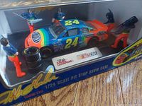 Detailed photo of the 1/24 scale Jeff Gordon NASCAR race car with four pit crew figurines in pit stop pose inside the display case.