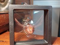 Front view of the oval quartz stone pendant displayed in a black square display box.