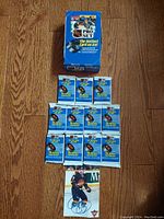 Photo showing original blue box for 1990 Series 1 NHL Pro Set and 11 unopened card packets arranged below it