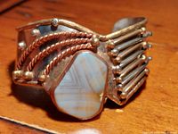 Close-up of the cuff bracelet showing agate stone and metal detailing on wooden surface.