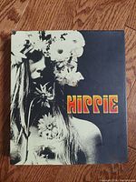 Front cover of vintage Hippie hardcover book with flower-adorned woman photo and retro title.