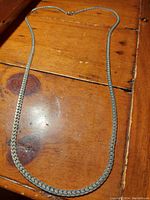 Full view of the necklace laid out on a wooden surface, showing length and general shape.