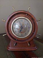 Front view of the vintage Seth Thomas nautical electric analog desk clock showcasing its wooden casing and brass handles.