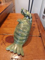 Side view of green nephrite jade walrus sculpture showing detailed carving and natural color variations.