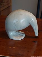 Side view of the light-colored stone sculpted Kiwi bird with detailed feet and long beak.