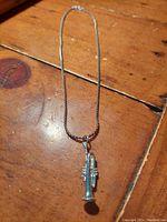 Photo of the full vintage sterling silver chain necklace with a trumpet pendant on a wooden surface.