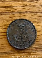 Obverse side of the 1852 Bank of Upper Canada one penny coin with crowned shield and crossed flags.