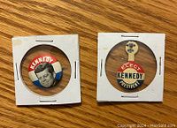 Front of two vintage John F. Kennedy pins, showing design and text details.