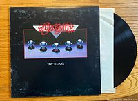 Front view of the Aerosmith Rocks album cover showing the band logo and artwork with the vinyl record partially inside a white inner sleeve.