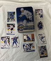 Top view of 2019-20 Upper Deck Series Two Auston Matthews collectible metal tin with 10 hockey cards arranged around it on white background.