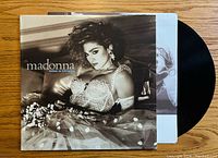 Front cover of Madonna's Like a Virgin vinyl album showing Madonna in a polka-dot wedding dress ensemble, lying on a bed.