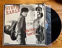 Front cover of the Steve Earle Guitar Town vinyl record album showing Steve Earle standing with a guitar, title and branding visible.