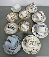 Overview of all 5 demitasse cup and saucer sets arranged on a table showing various floral and gold-trimmed designs