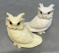 Pair of vintage alabaster owl sculptures, one cream-colored and one white, viewed from front and side angles showing detailed carving and eyes.