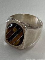 Front angle showing tiger's eye stone and metal stripe inlay in silver ring.