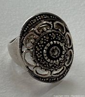 Close-up front view of the sterling silver ring showing detailed raised filigree pattern and beaded texture.