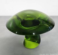 Top view of the green mushroom-shaped Viking glass paperweight showing the wide, rounded cap with slight surface texture.