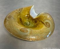Murano glass bowl or ashtray, showing moonstone color with gold flecks and swirling patterns, displayed on neutral surface.