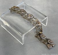 Full view of the sterling silver filigree lily bracelet displayed on clear stand showing overall design and length.