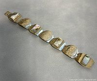 Full length of the vintage bracelet showing silver panels with embossed western motifs alternating with abalone shell panels.