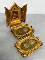 Overall view of the triptych and two frames with medallions arranged on a gray surface.