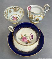 Lot with Paragon creamer and sugar bowl and Aynsley teacup set shown on grey suede background.