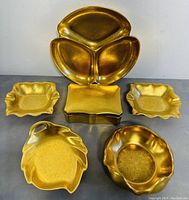 Full set of six gold etched porcelain dishes shown on plain surface.