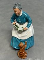Front view of the figurine showing the elderly woman with a cat reaching up.