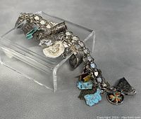 Side angle showing full length of vintage silver charm bracelet with various charms attached