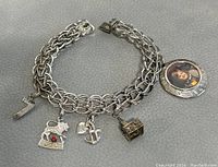 Photo of the full charm bracelet laid flat showing all five charms and the chain links with clasp