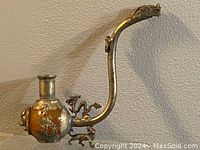 Side view showing the pipe's curved copper stem with a dragon head and body wrapping around the pipe bowl made of jade-like amber material.