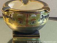 Close-up of antique Nippon porcelain ashtray front view showing gold and green face design with detailed eyes and ornamental accents