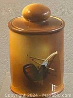 Photo front view of the porcelain tobacco jar showing the hand painted tobacco pipe and matchstick