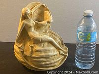 Full view of Art Nouveau ceramic vase next to a water bottle for scale, showing seated female figure and flowing leaf design.