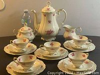 Set arranged on table including coffee pot, creamer, sugar bowl, 5 cup and saucer sets.