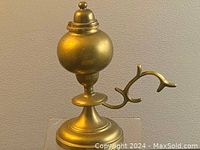 Side view of the solid brass oil lamp showing rounded reservoir and curved handle.