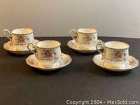 Four Royal Albert teacups with matching saucers arranged on black surface, showing front and handle details.